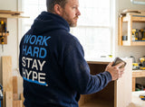 Man wearing a navy hoodie with motivational text in a workshop setting